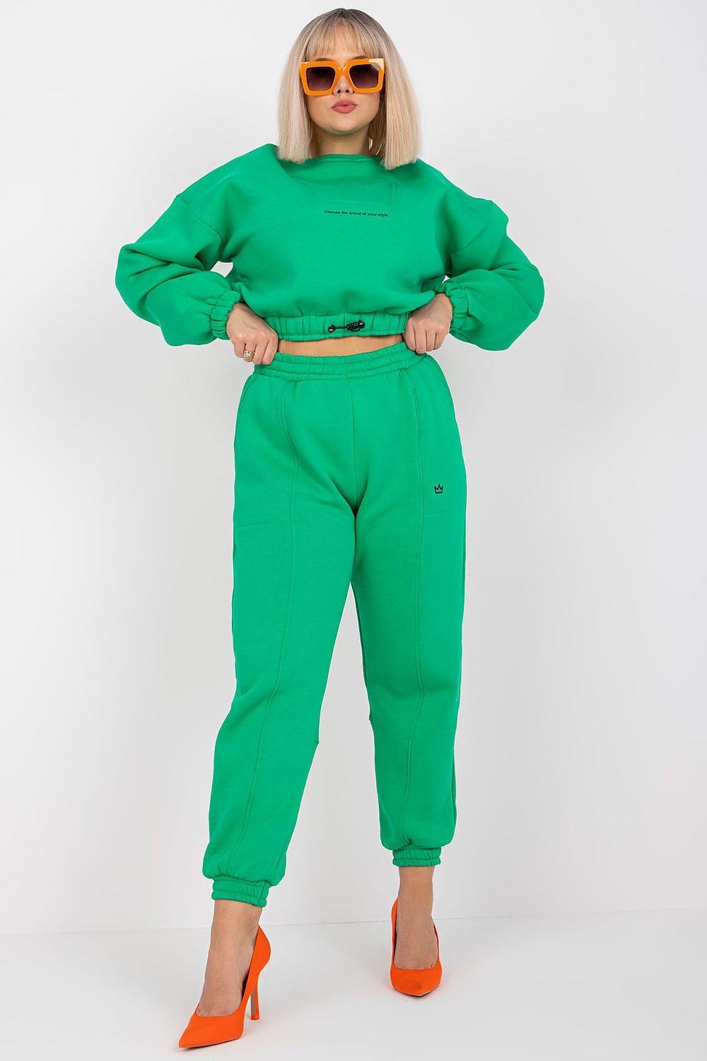 Ex Moda Cotton Blend Sweatshirt Set with High-Waist Trousers – Elegant Loungewear Outfit featuring a model styled in a vibrant green cropped sweatshirt and high-waist trousers, complemented by bright orange heels and oversized sunglasses in a luxurious and chic setting.