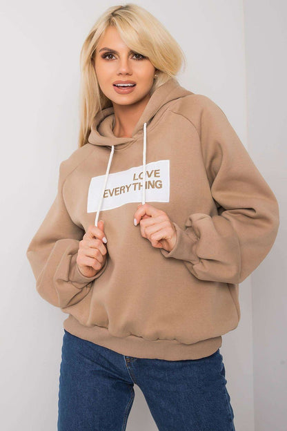 Ex Moda Women's Hooded Sweatshirt - Stylish long sleeve design with decorative inscription, model posing in a beige sweatshirt featuring 'LOVE EVERYTHING' print.
