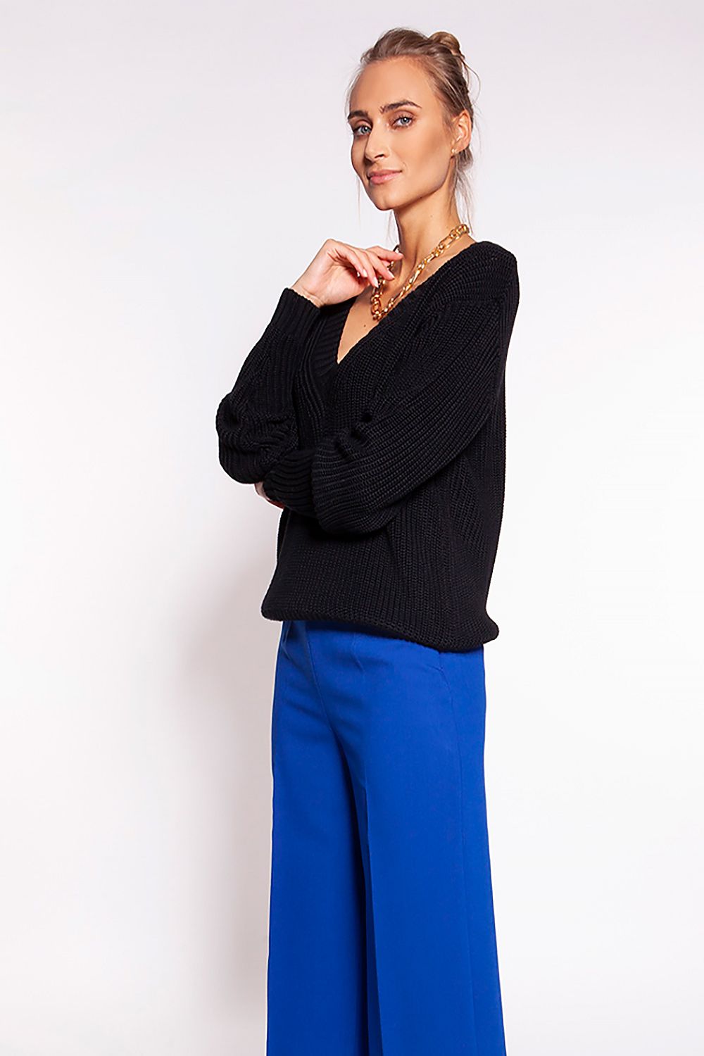 Luxurious Minimalist Ribbed Knit Jumper with Deep Heart Neckline by MKM, showcased in black, paired with royal blue trousers, highlighting its casual yet elegant style.