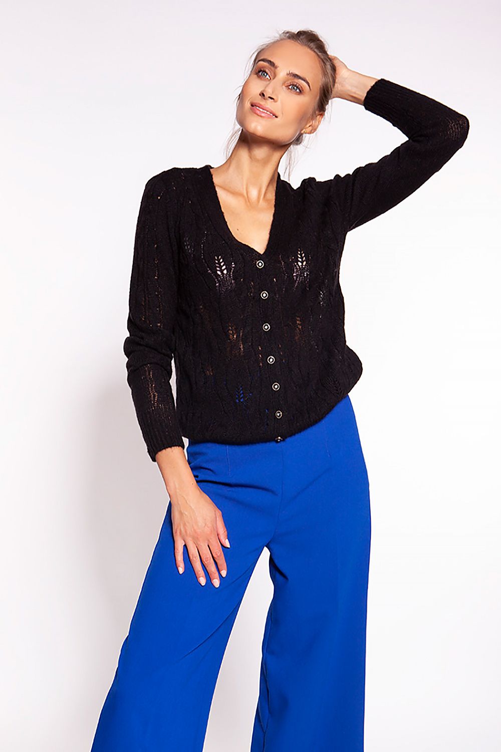 Elegant MKM Unbuttoned Cardigan with Deep V-Neck and Intricate Openwork Design, presented by a model in a chic black cardigan, pairing beautifully with vibrant blue trousers, embodying elegance.