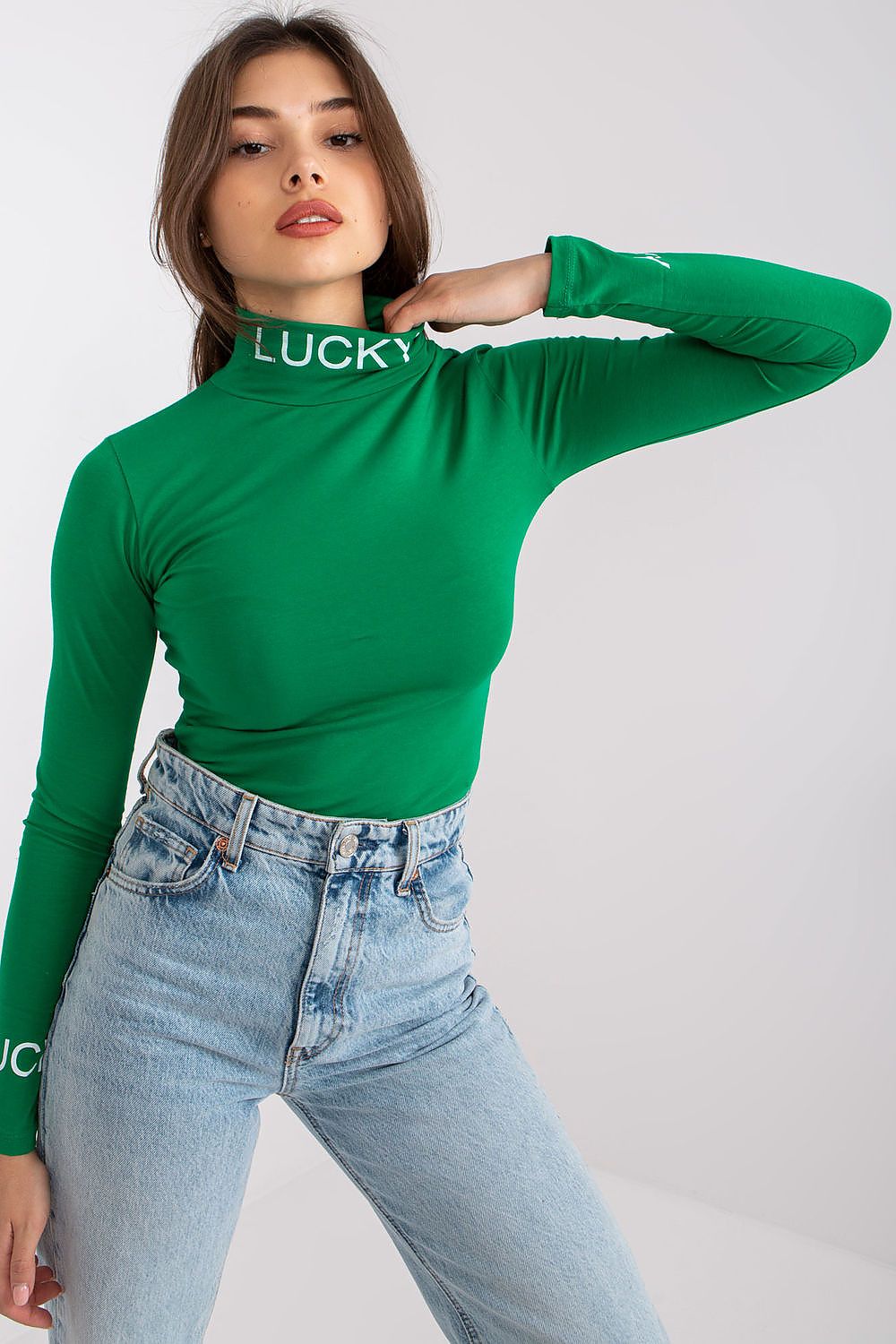 Glamorous appearance of a model in the Elegant Cotton Blouse with Long Sleeves and Turtleneck by Ex Moda. The vibrant green hue and fitted design with contrast lettering create an eye-catching ensemble with trendy high-rise denim.