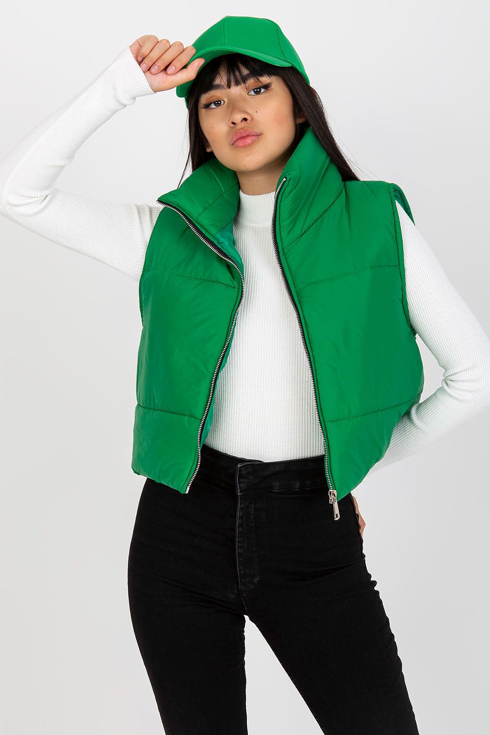 Elegantly styled Och Bella Women's Insulated Quilted Vest - Short Zippered Nylon Gilet, showcased in vibrant green, paired with a white knitted top and a chic green cap, exuding contemporary fashion.