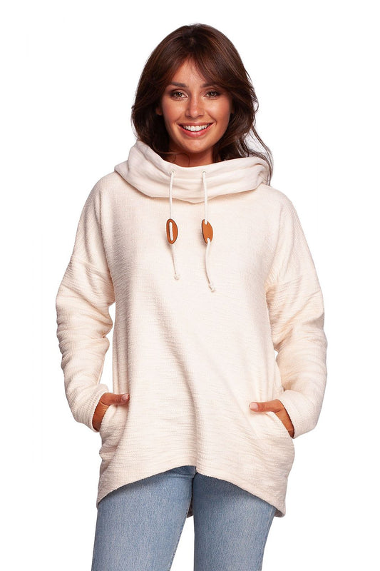 BeWear Oversized Cotton Blend Hooded Sweatshirt Tunic for Comfortable Cold Weather, featuring a luxurious cream colour, a cosy hood, and side pockets, modelled by a smiling woman.