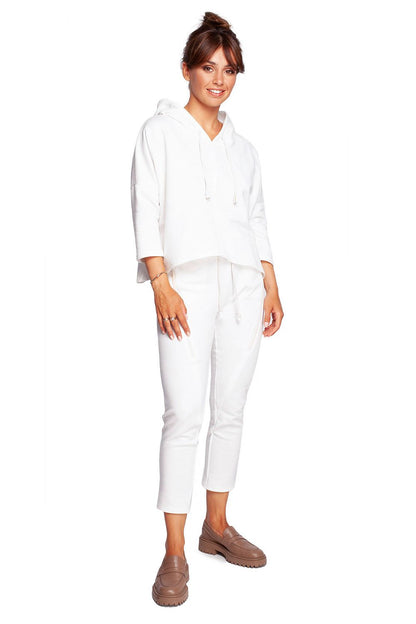 Model showcasing the BeWear Loose-Fitting Trapeze Sweatshirt in Soft Knit with Hood and Faux Leather Accents, paired with matching white trousers, exuding elegance and comfort.
