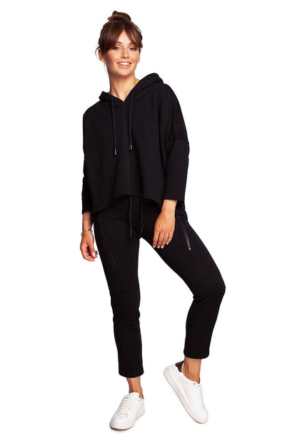 Full body view of the BeWear Loose-Fitting Trapeze Sweatshirt in Soft Knit with Hood and Faux Leather Accents, styled with black trousers for a sophisticated loungewear ensemble.