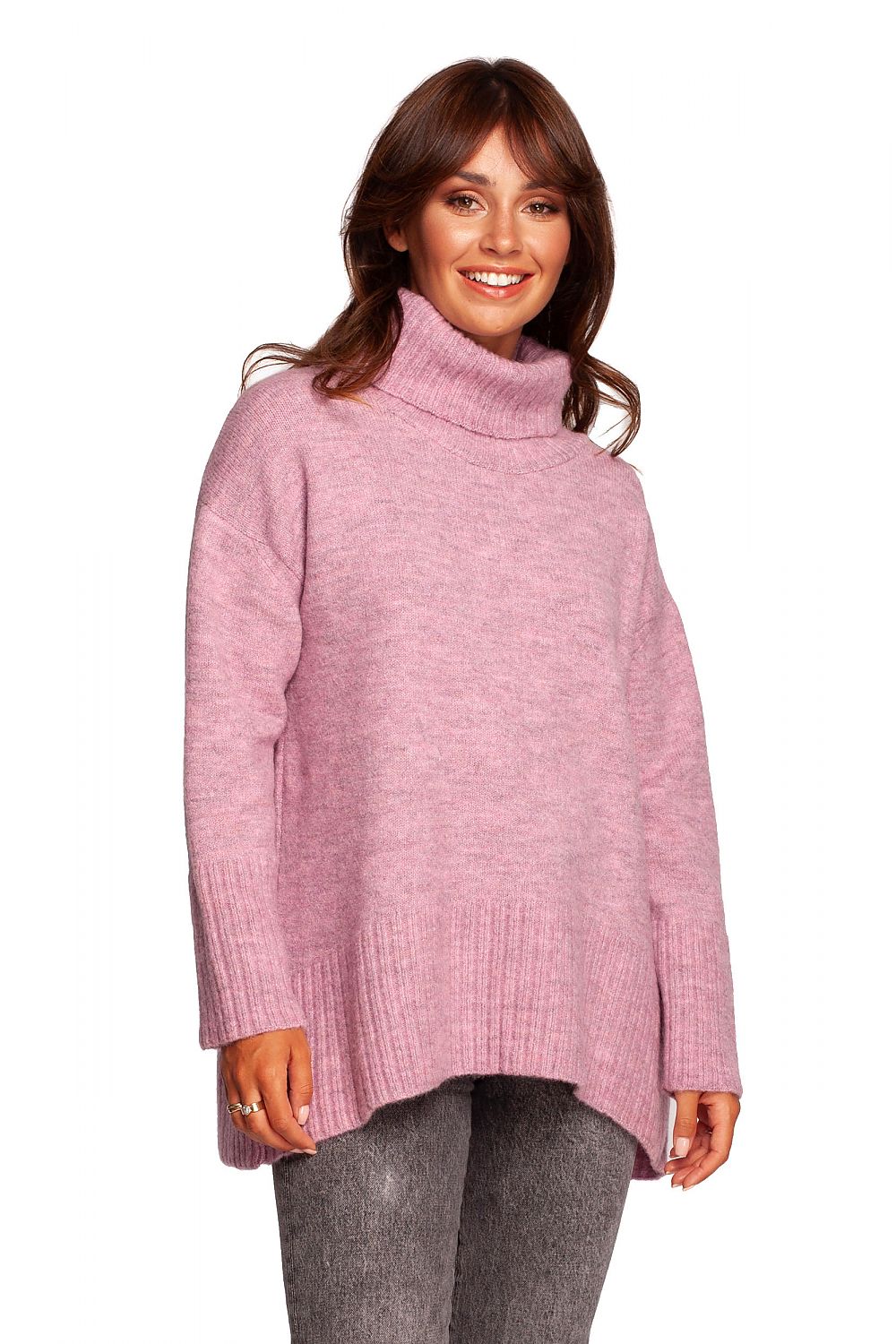 Model showcasing a luxury turtleneck knit sweater with ribbed hem and back slit in soft pink, highlighting the elegant design and warm acrylic blend fabric.