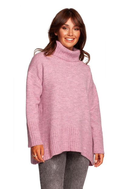 Model showcasing a luxury turtleneck knit sweater with ribbed hem and back slit in soft pink, highlighting the elegant design and warm acrylic blend fabric.