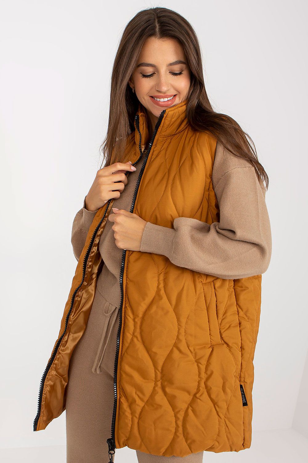 Stylish model wearing the Luxurious Quilted Zippered Gilet With Slip Pockets by Rue Paris, showcasing its elegant quilted design and soft fabric in a warm mustard hue.