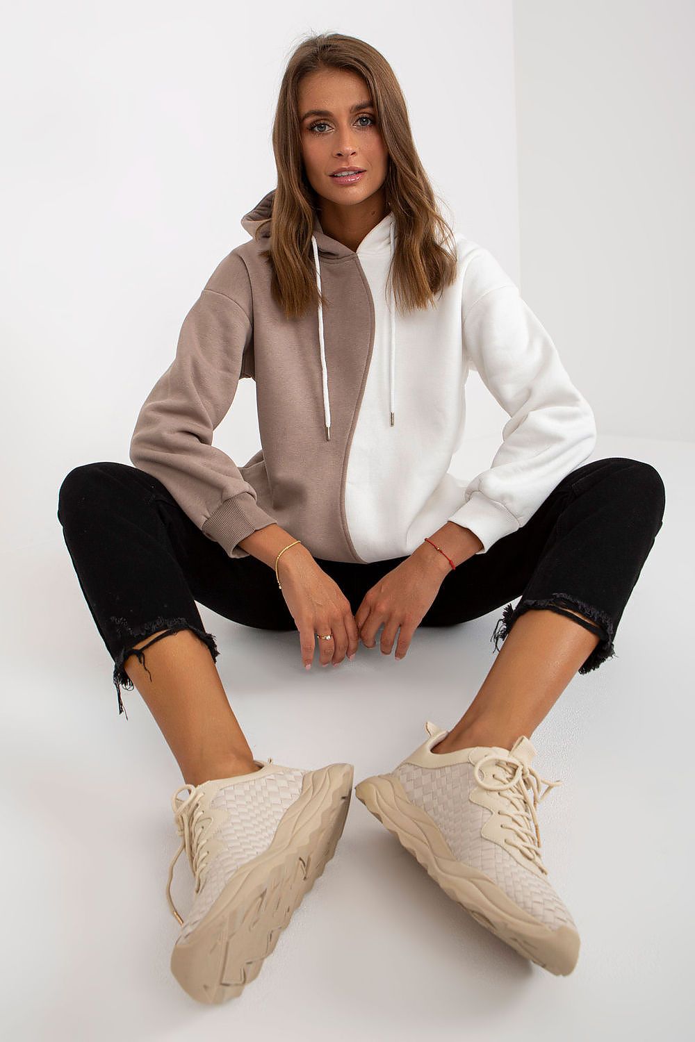 Luxurious Two-Colour Women's Hoodie Sweatshirt by Rue Paris with Slip Pockets, featuring a stylish brown and white contrast, model seated with casual pants and sporty shoes.
