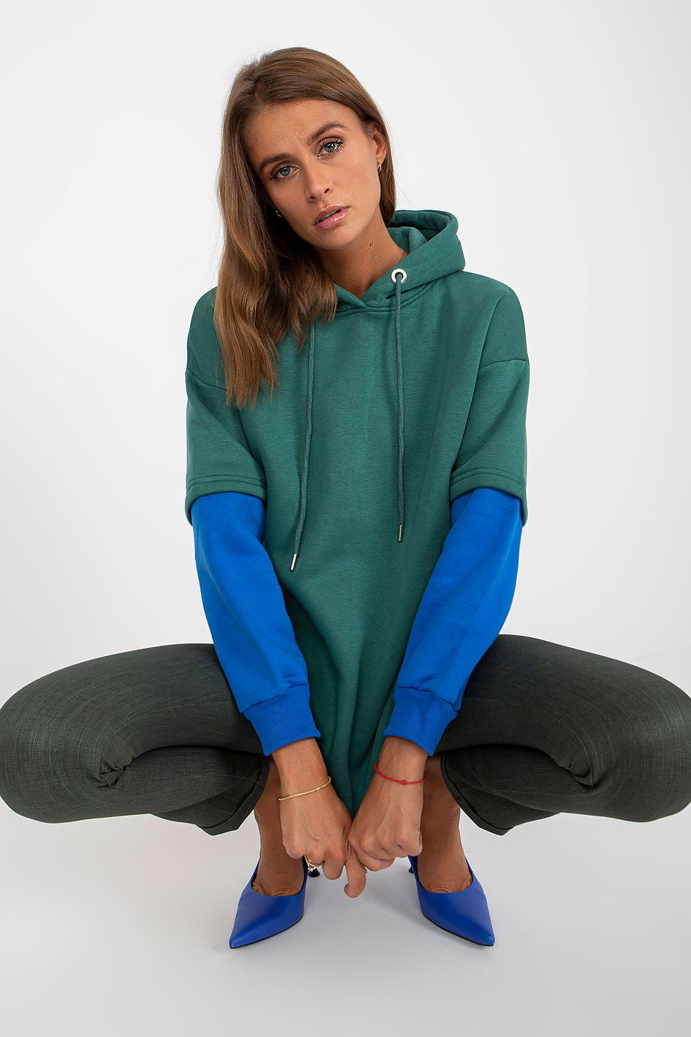 Luxury Women's Rue Paris Cotton Blend Sweatshirt with Hood, Extended Cut and Long Sleeves - Chic model kneeling, highlighting the vibrant green hoodie with contrasting blue sleeves.