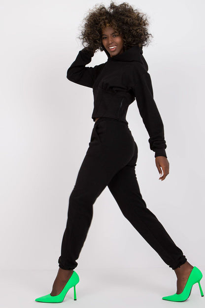 Luxury Ex Moda Cotton-Blend Sweatshirt Set with Corset Insert & Elastic Waist Pants displayed by a model, highlighting the elegant black crop sweatshirt with hood and elastic waist pants, paired with bright green heels.