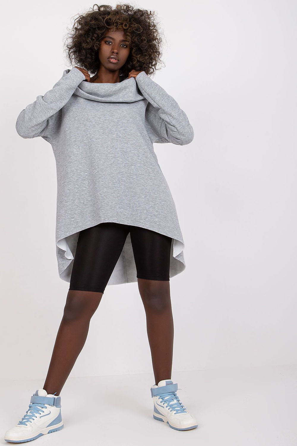 Ex Moda Women's Hooded Sweatshirt showcased on a model, featuring long sleeves and a loose fit with an asymmetrical hem. The aesthetically pleasing grey fabric combines comfort and style, made from a luxurious mix of cotton, spandex, and polyester.