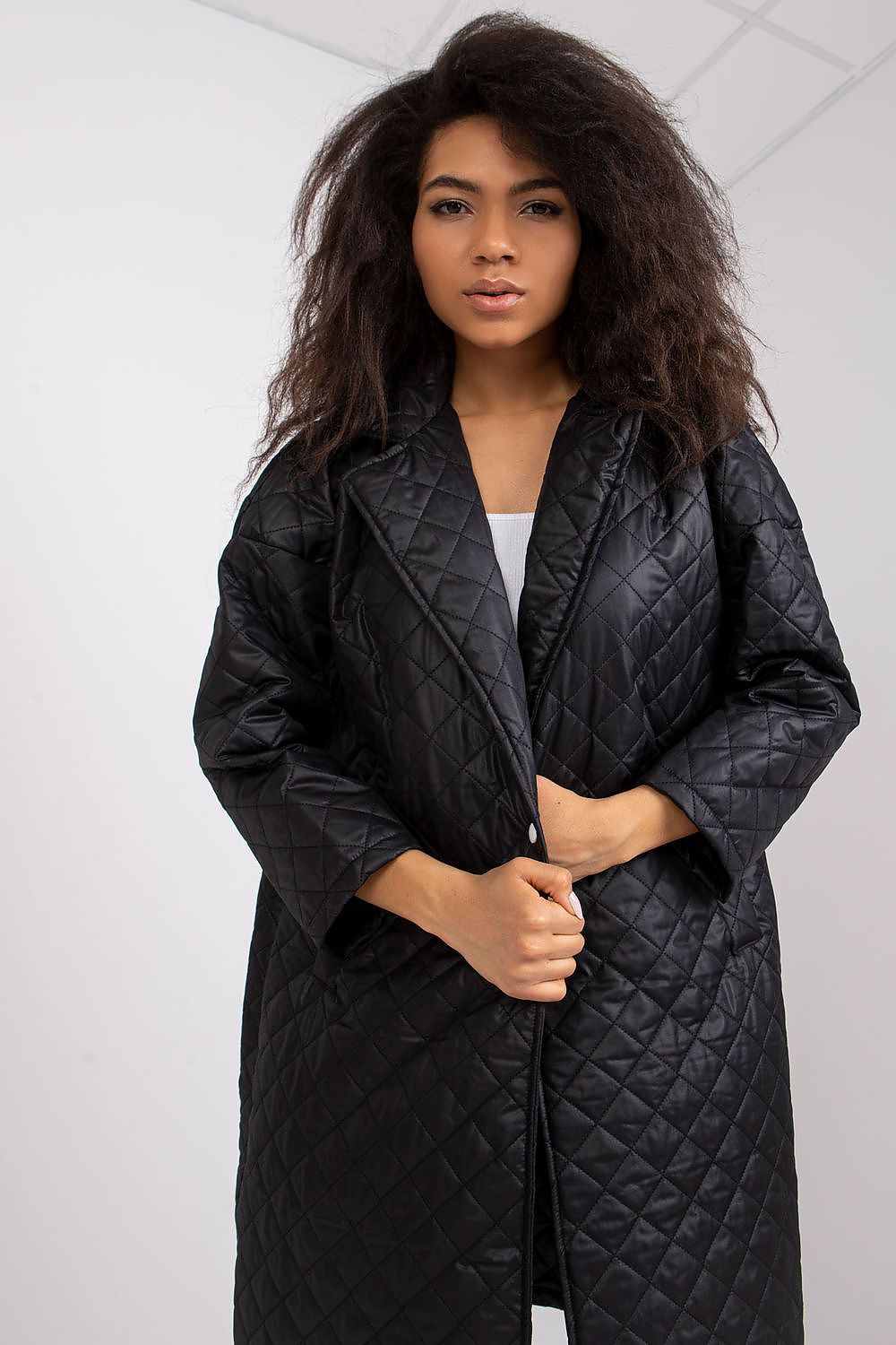 Ex Moda Quilted Long Sleeve Coat in 100% Polyester, showcasing a model with tousled hair, exuding elegance while holding the coat closed, featuring a sophisticated quilted design.