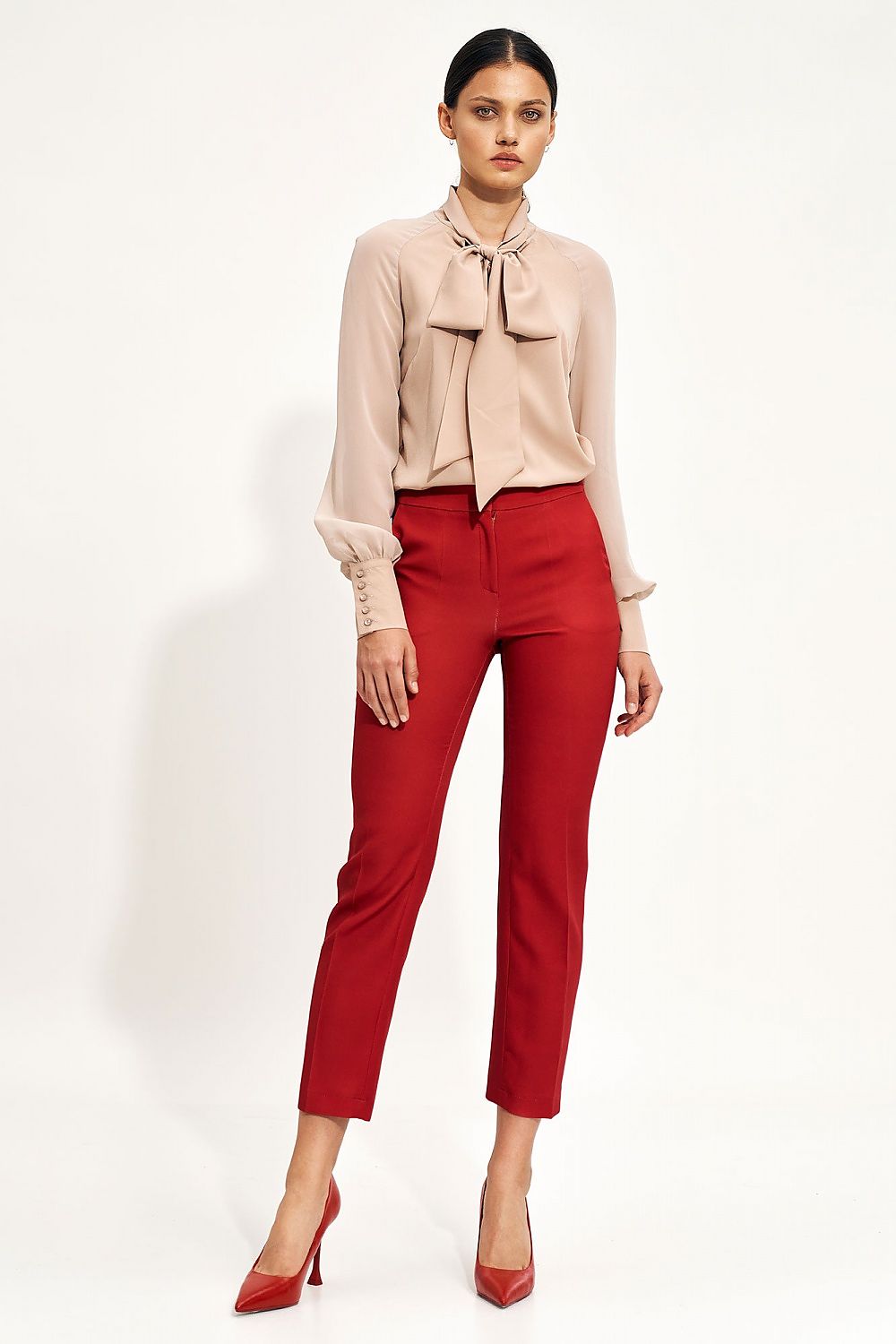 Sophisticated blush blouse with a decorative neck tie and wide cuff sleeves by Nife, elegantly paired with red tailored trousers for a striking ensemble.