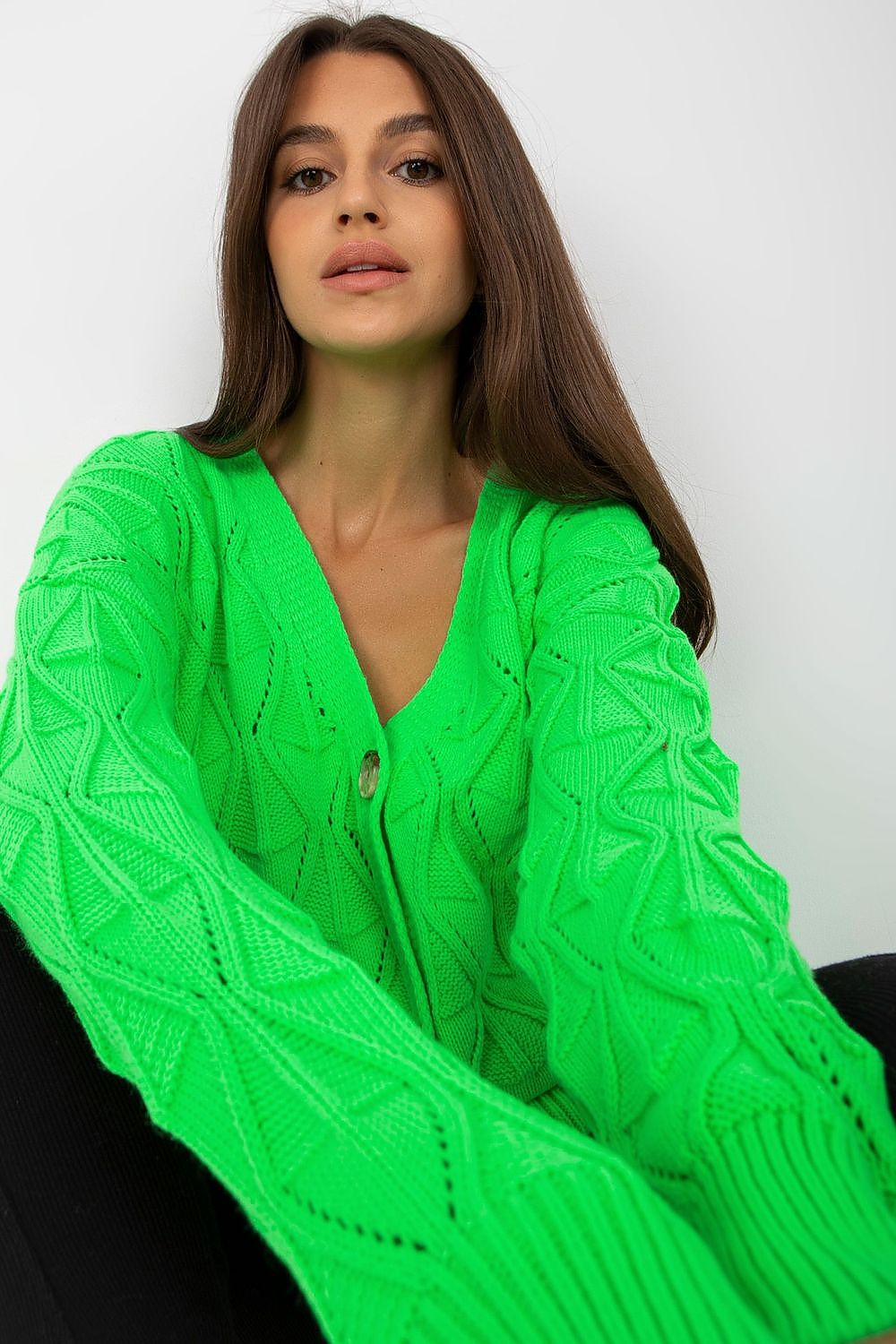Luxurious Women's Button-Down Cardigan Sweater by Rue Paris with Openwork Pattern, showcasing a close-up of the model lounging comfortably in a vibrant green cardigan, emphasising the detailed knit texture.