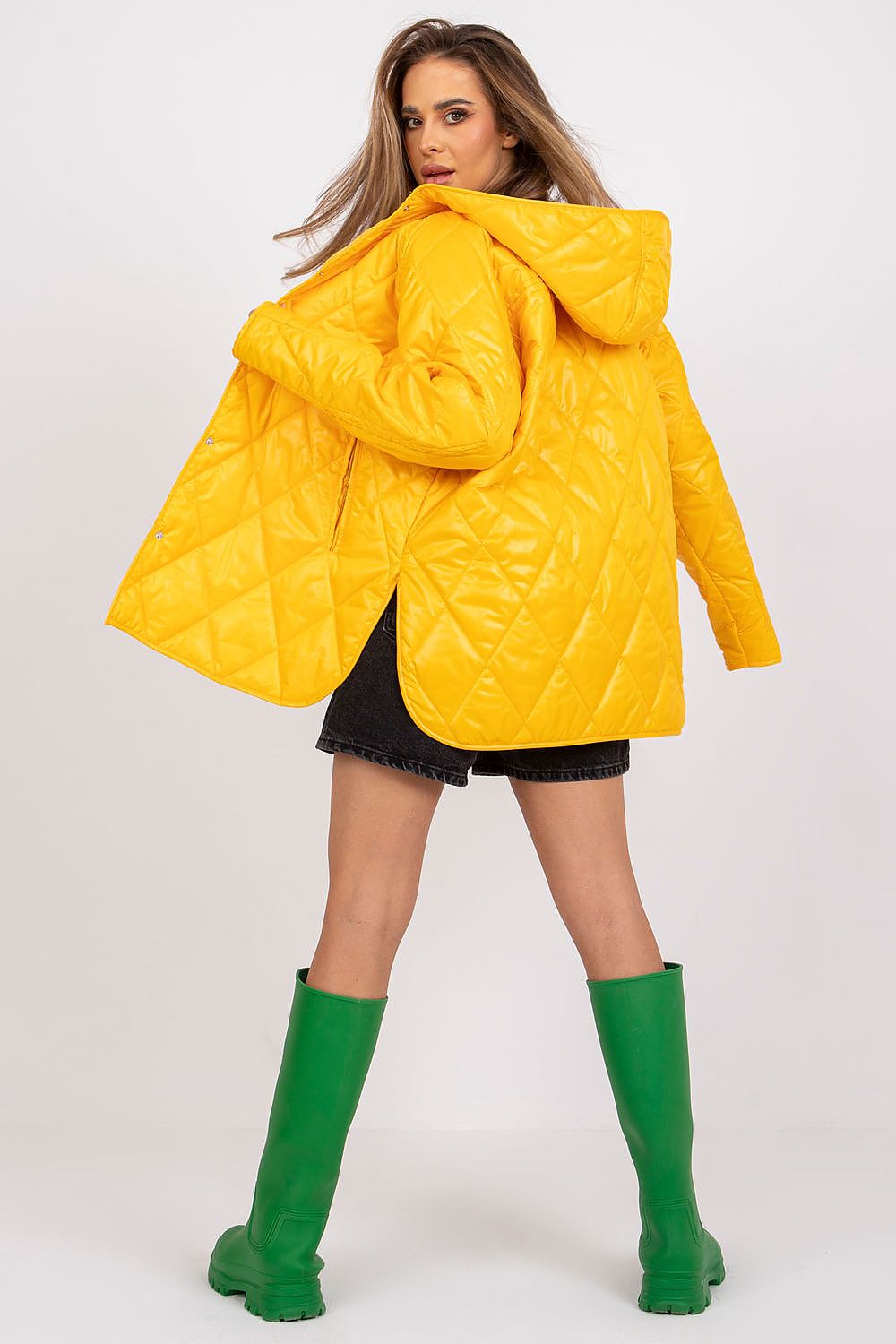 Stylish back view of Women's Quilted Hooded Jacket by Rue Paris, highlighted in radiant yellow, ideal for maintaining luxury in transitional seasons, combined with stylish green rain boots.