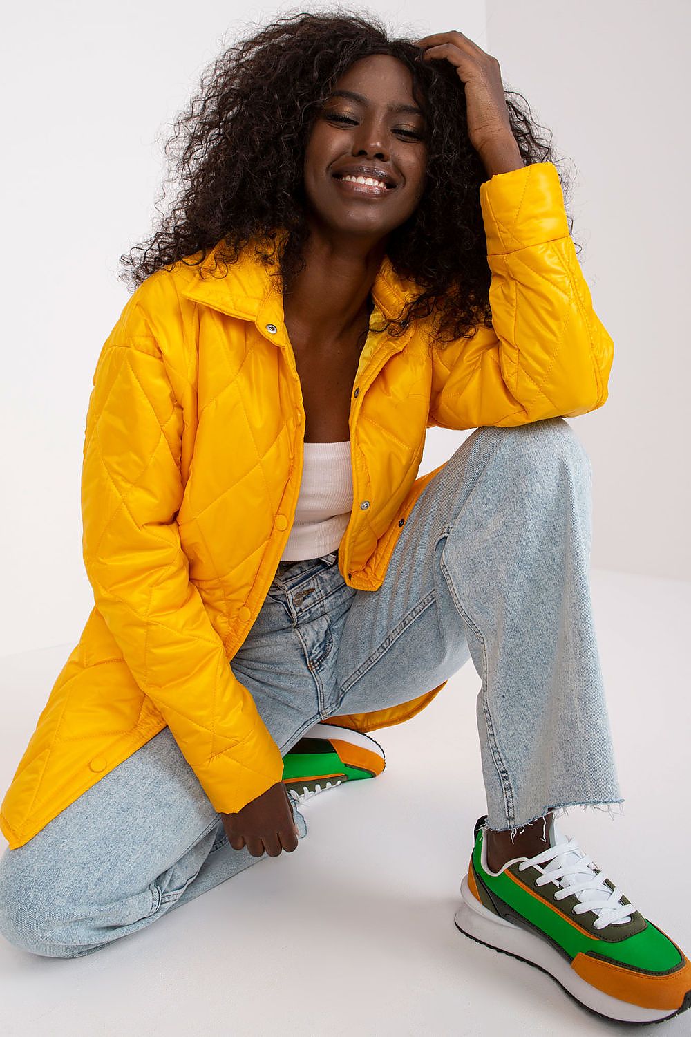 Charming image of a woman showcasing the Elegant Women's Quilted Jacket by Rue Paris, bright yellow in colour, styled with casual jeans, exuding a chic vibe suitable for the transitional season.