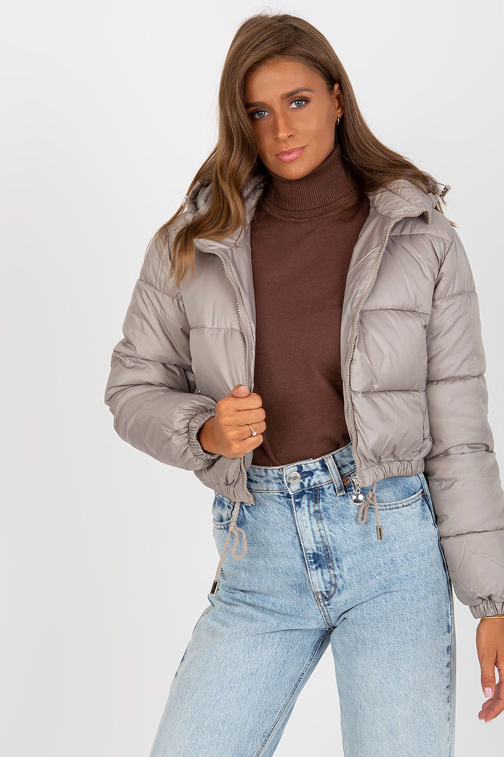 Luxury Women's Down Quilted Jacket with Detachable Hood and Zippered Pockets, elegantly styled with a turtleneck sweater and high-waisted denim, showcasing a chic, sophisticated look.