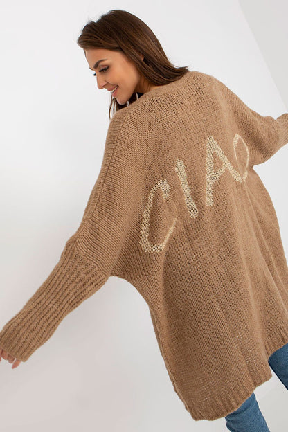 Chic portrayal of a model in the Och Bella Unbuttoned Cardigan with Long Wide Sleeves and Contrasting Lettering, featuring a luxurious brown tone and stylish ‘CIAO’ lettering.