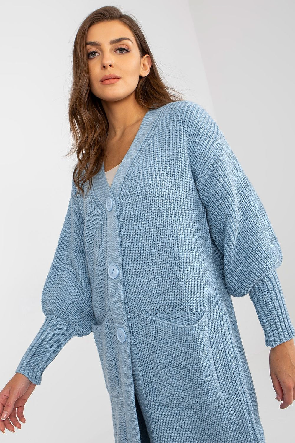 Elegant Stylish Long Buttoned Cardigan With Pockets, crafted from 70% Polyester and 30% Wool, showcased on a model, featuring a soft blue hue and a relaxed fit, ideal for layering in sophisticated winter outfits.