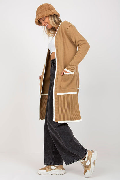 Luxury Women's Unbuttoned Long-Sleeve Cardigan with Pockets by Rue Paris, model wearing a caramel cardigan with contrasting white details, over a white crop top and dark trousers, reflecting a trendy and sophisticated look.