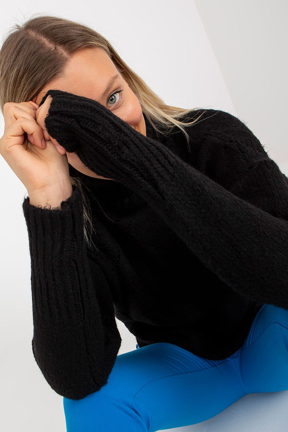 Close-up of the Luxurious Openwork Turtleneck Sweater by Rue Paris, highlighting its intricate design and long sleeves, complemented by bright blue trousers for an elegant fashion statement.