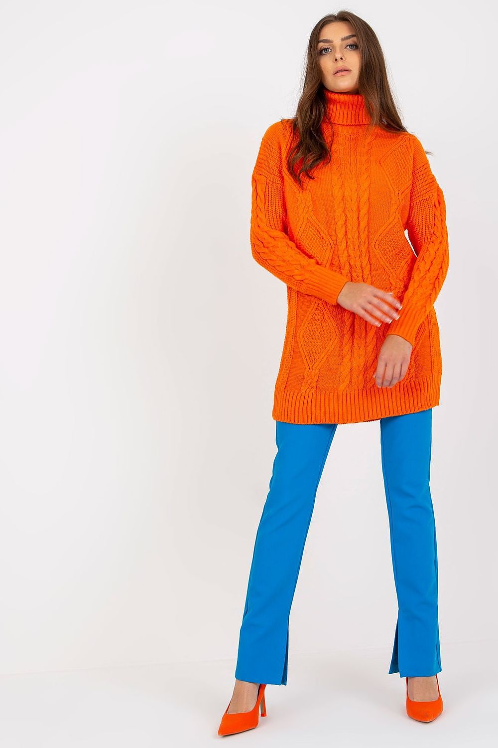Luxurious Rue Paris Women's Long Turtleneck Jumper in vibrant orange, paired with sleek blue trousers and high heels, showcasing trendy high fashion.