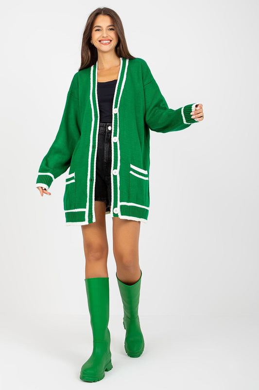 Luxury long-sleeved acrylic cardigan with button closure and contrast trim by Rue Paris, styled with a playful smile and paired with stylish green boots, showcasing a chic and vibrant look.