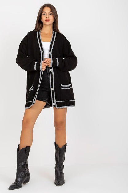 Luxury Long-Sleeved Acrylic Cardigan With Button Closure And Contrast Trim by Rue Paris, featured in classic black, effortlessly styled with shorts and knee-high boots for a fashionable appearance.