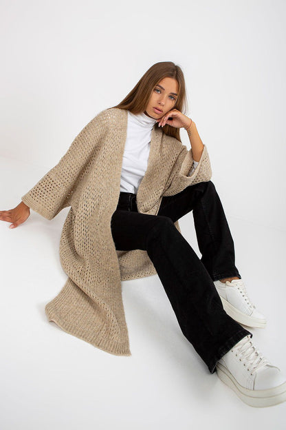 Chic and refined Elegant Openwork Long Sleeve Cardigan by Och Bella, showcased elegantly while seated, layered over a turtleneck, complemented by relaxed black trousers and trendy sneakers, epitomising luxury knitwear.