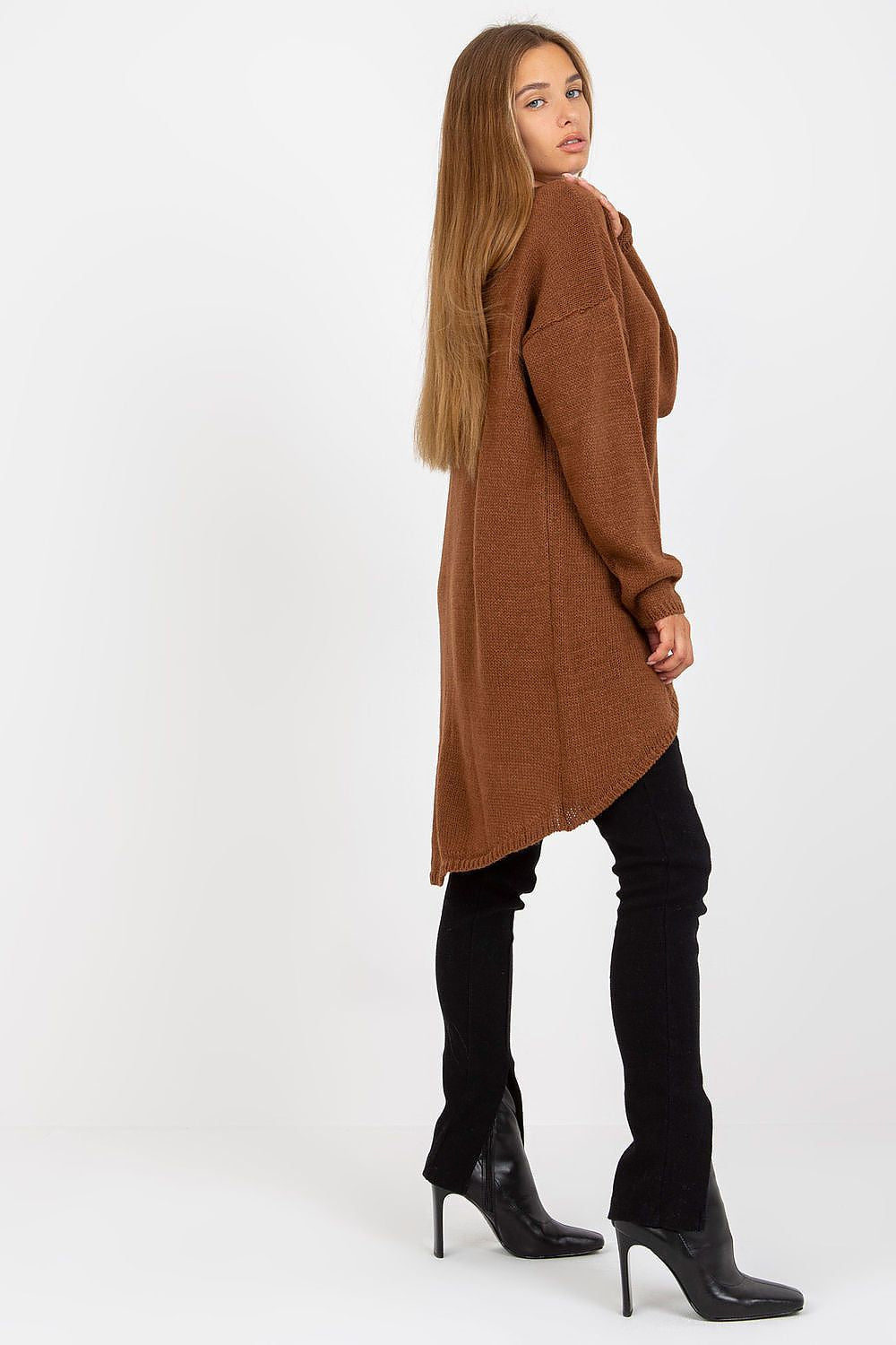 Luxury Women’s Asymmetrical Cut Sweater by Och Bella, model from the side wearing a brown sweater with an extended cut, paired with black fitted pants, exuding a chic and sophisticated vibe.