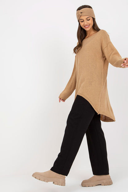 Luxury Women’s Asymmetrical Cut Sweater by Och Bella, model smiling in a beige asymmetrical sweater, styled with black trousers and a headband, reflecting a fashionable and comfortable look.