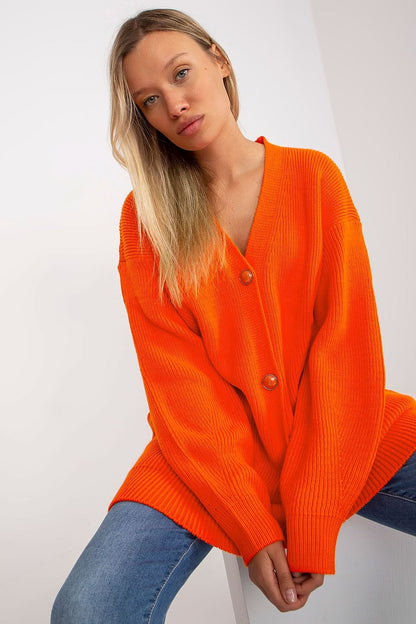 Elegant Extended Cut Cardigan by Rue Paris in vibrant orange, featuring a button closure and long sleeves, styled effortlessly with casual denim for a chic appearance.