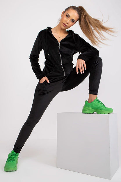 Model showcasing a luxurious black velour loungewear set with a zippered hooded sweatshirt and fitted long pants, paired with vibrant green athletic shoes for a stylish contrast.