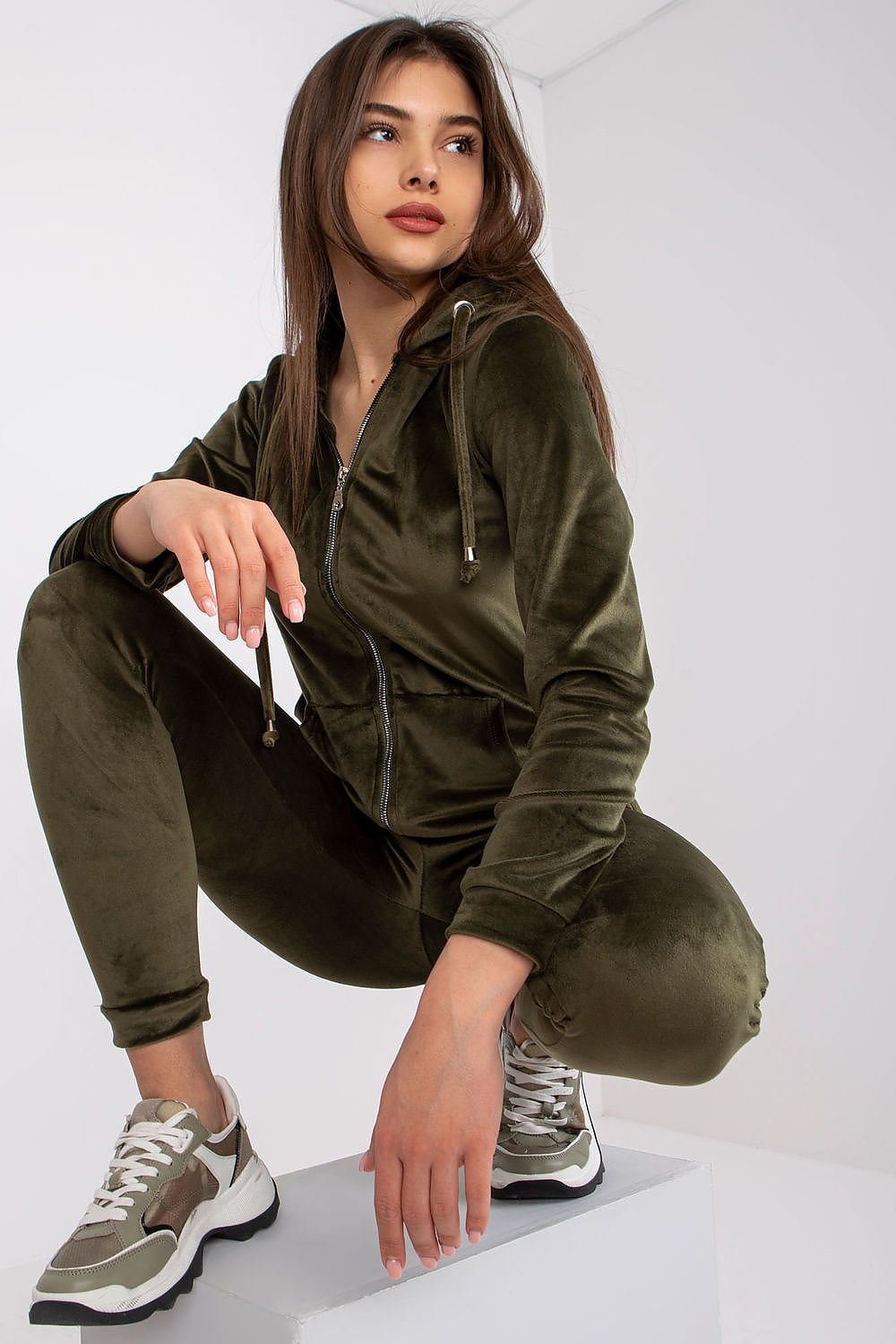 Chic model showcasing a hooded velour sweatshirt and matching long pants, exuding comfort and sophistication in an olive green ensemble.