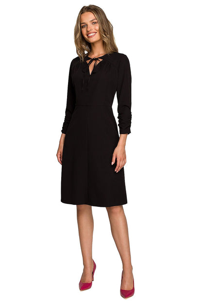 Sophisticated black daydress with a flattering silhouette, elegantly adorned by a model, ideal for upscale events.