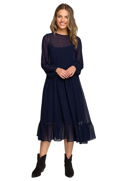 Stylish woman in a navy chiffon cocktail dress with ruffled waistline and wide elastic sleeves, standing confidently in an elegant pose, perfect for evening wear.