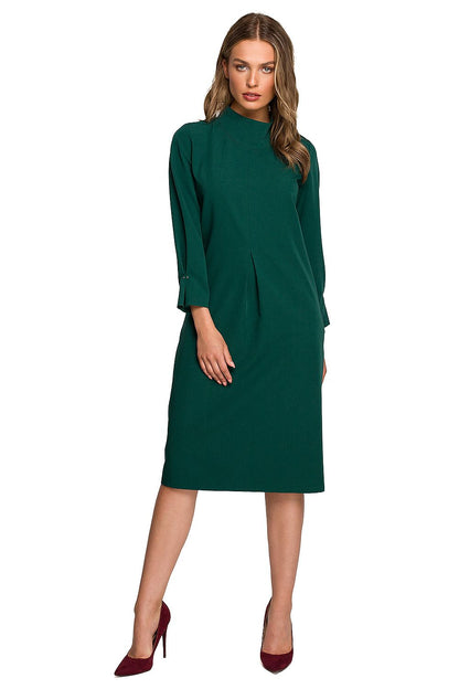 Stylove elegant day dress featuring a high collar, pleated details, and a covered zipper, showcased on a model in a rich emerald green. Perfect for sophisticated daytime outings.