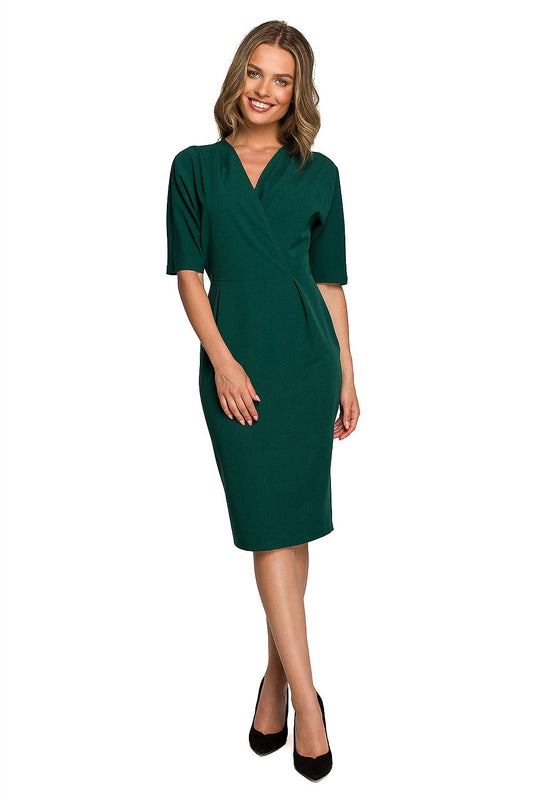 Stylish woman models a luxurious green envelope top daydress with batwing sleeves and a sleek pencil bottom, exuding elegance and sophistication.