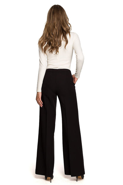 Elegant back view of Stylove women's black wide cropped trousers with a low-fitting waist, paired with a sleek white long-sleeve blouse, radiating a contemporary feminine style.