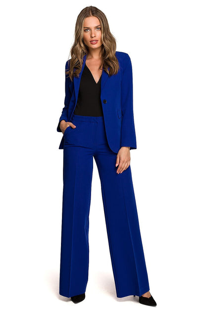 Confident woman wearing a striking blue one-button waist jacket with matching trousers, exuding elegance and modern sophistication.