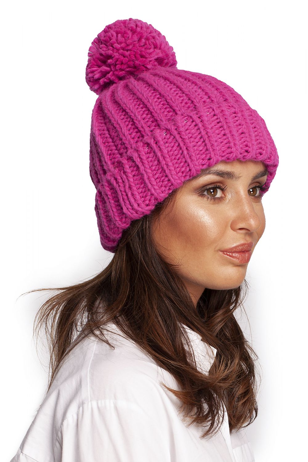 Profile view of a chic pink pom-pom beanie hat made from high-quality yarn, worn by a model, highlighting its sophisticated texture and contemporary winter style.