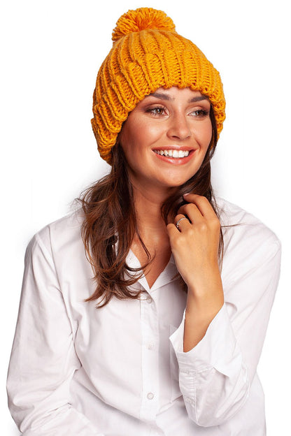 Luxurious pom-pom beanie hat in vibrant orange, paired with a classic white shirt, exuding warmth and style for winter fashion.