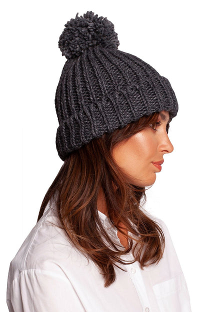 Side view of a sophisticated dark grey pom-pom beanie, highlighting its stylish ribbed design for contemporary winterwear.