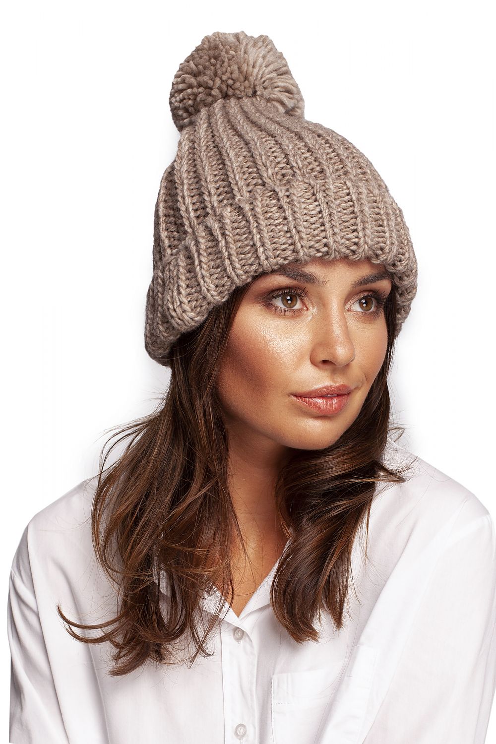 Chic beige pom-pom beanie hat displayed on a model, radiating luxury and comfort, ideal for complementing winter attire.