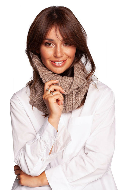 Fashionable woman beaming in a stylish beige infinity scarf, perfect for effortless warmth and elegance in autumn.