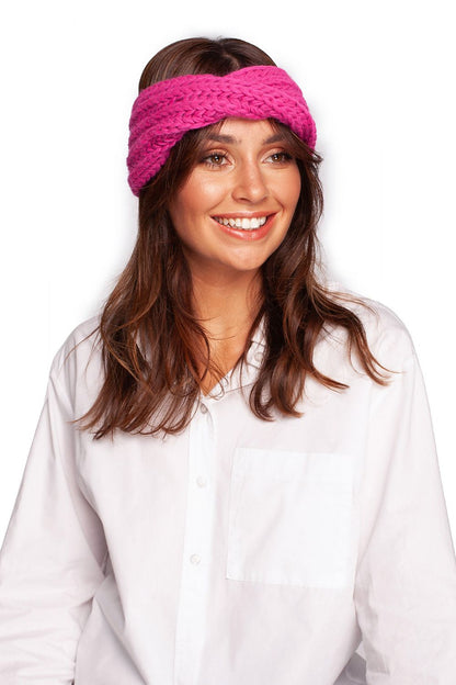 Luxurious pink knitted headband by BE Knit, showcased on a smiling model wearing a white blouse, perfect for stylish winter warmth.