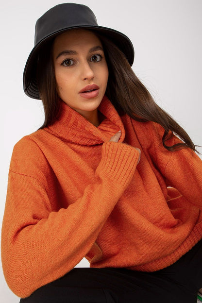 Close-up view of a model wearing an elegant rust-coloured turtleneck sweater by Rue Paris, showcasing its luxurious fabric and stylish design, paired with a chic black hat.