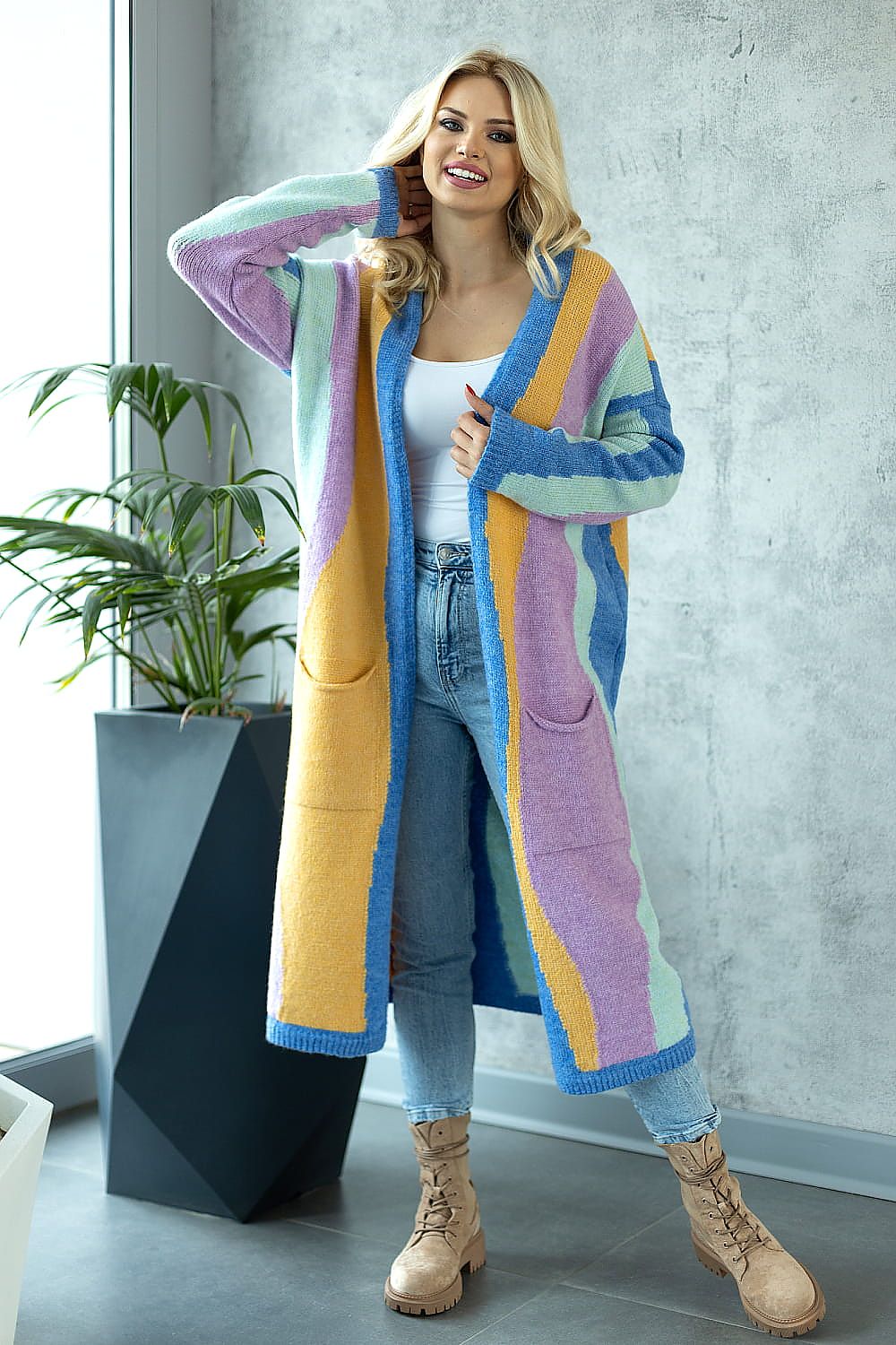 Stylish long cardigan in soft pastel colours, paired with denim, radiating comfort and elegance, surrounded by contemporary décor.