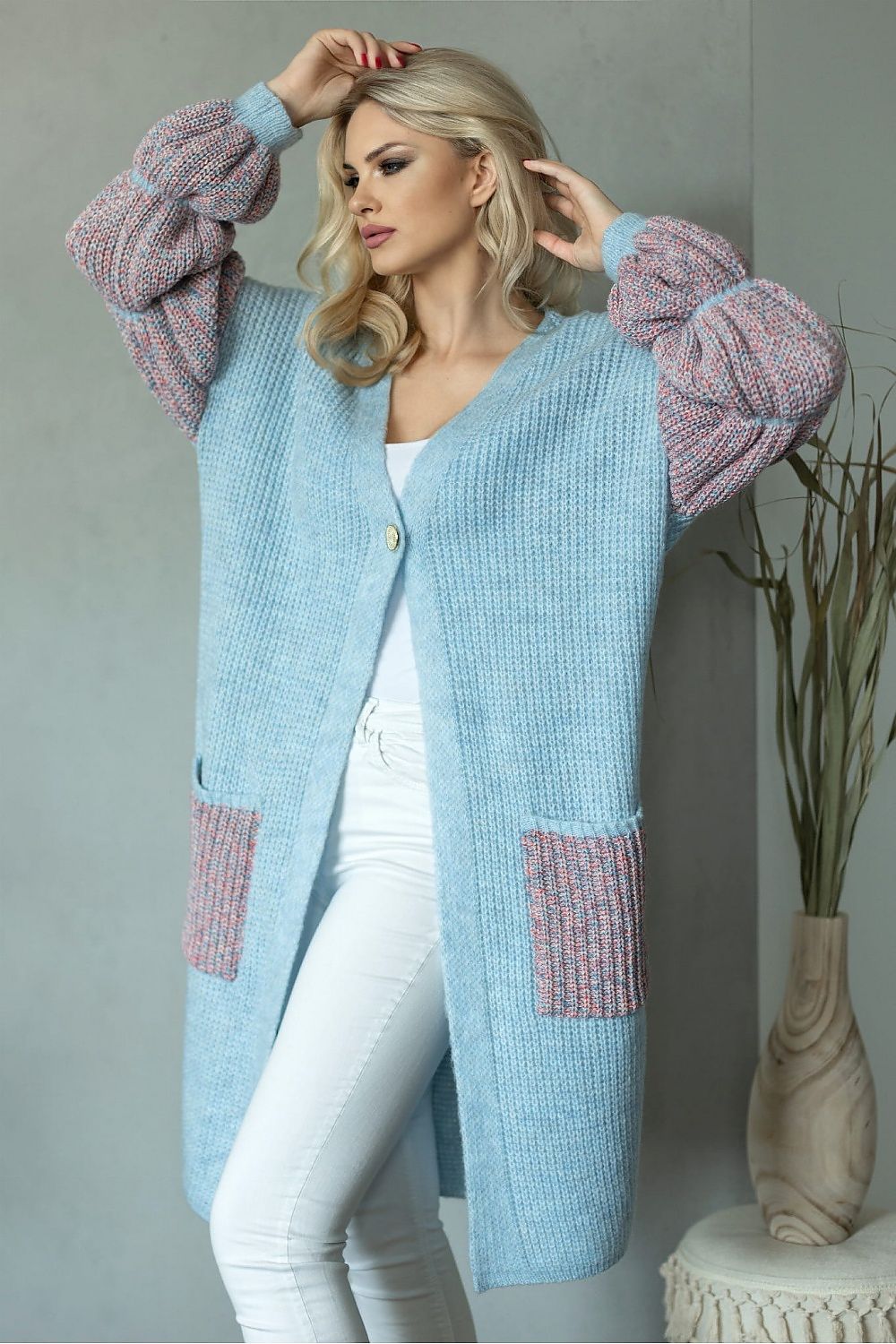 Luxurious long sleeve cardigan in soft blue wool blend with stylish puffed sleeves, featuring a single button closure and practical side pockets, elegantly showcased against a minimalist backdrop.